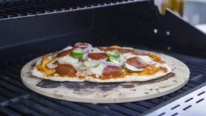 The pizza stone is baking pizza on the grill