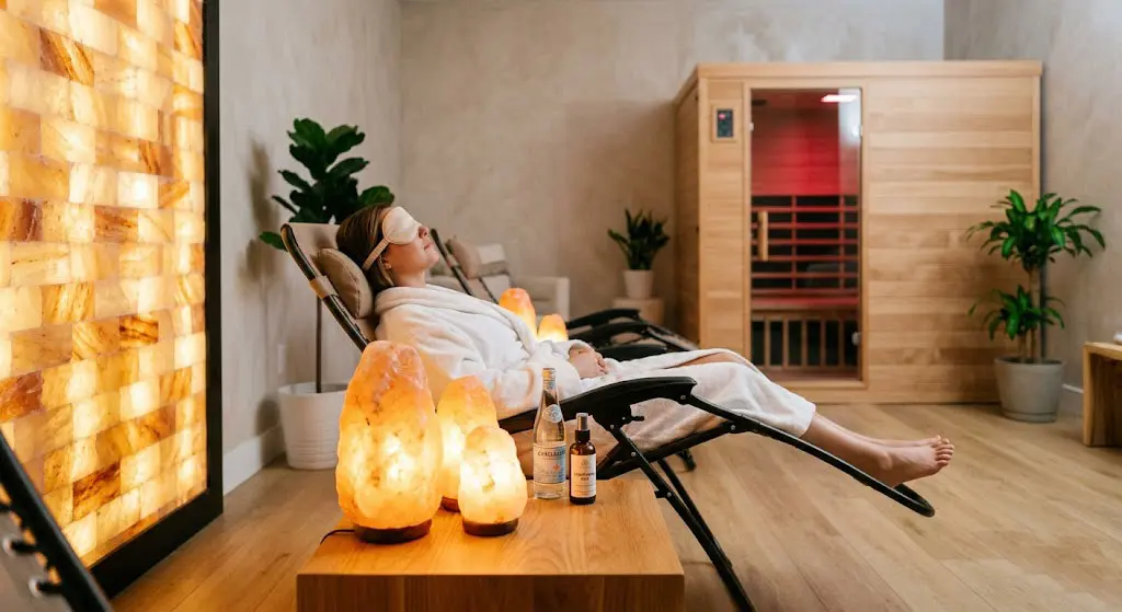 A modern wellness center featuring Himalayan salt therapy integrated with an infrared sauna, showcasing glowing amber salt lamps and a salt brick wall for relaxation.