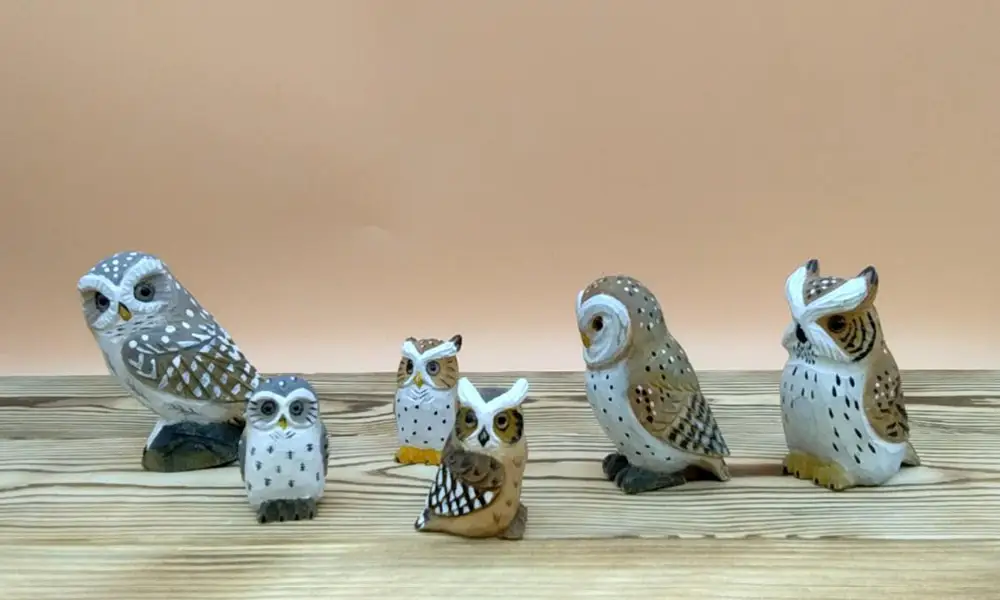 A varied collection of hand-carved wooden owls in multiple species and sizes, ranging from small figurines to larger shelf decor.