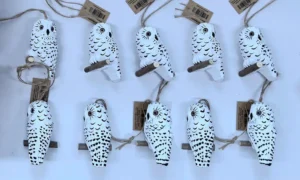 Hand-painted white snowy owl wooden ornament with dark feather specks and natural jute hanging string.