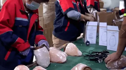 workers in red uniforms on a factory production line assembling natural shaped Himalayan salt lamps