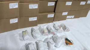 Handcrafted wood carvings individually wrapped in protective silk tissue paper alongside stacked inner boxes with product label tags.