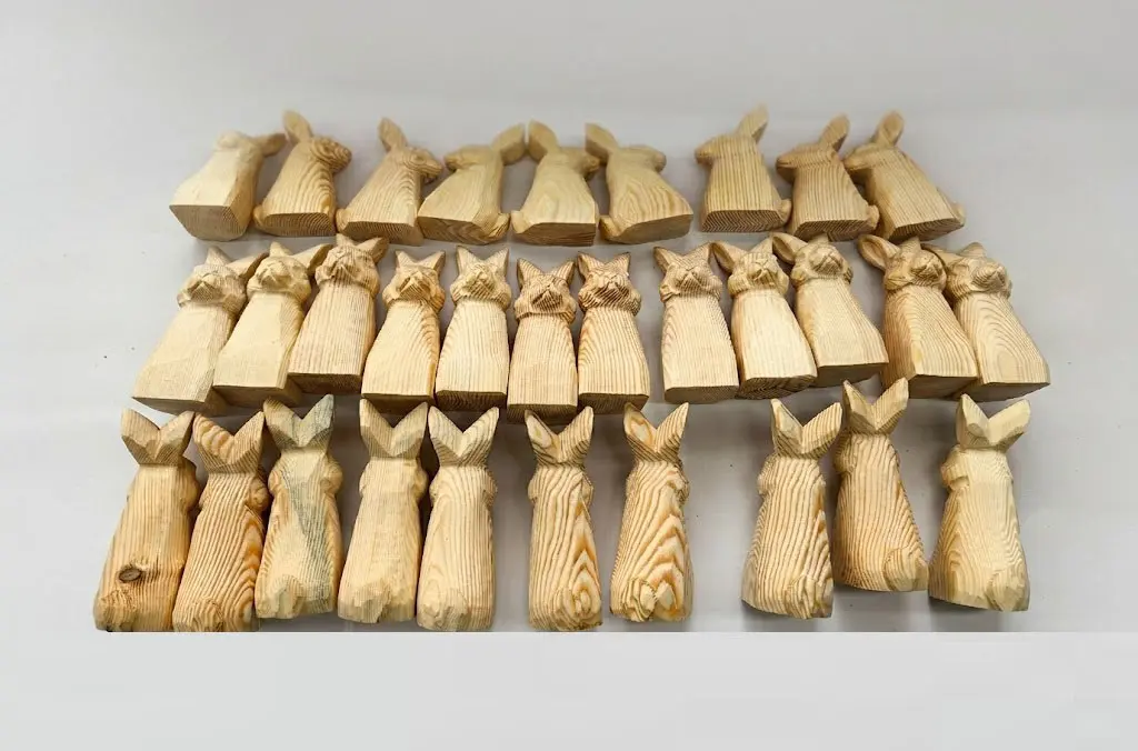 Twenty-seven identical hand-carved wooden rabbit figurines showing template consistency for mass production
