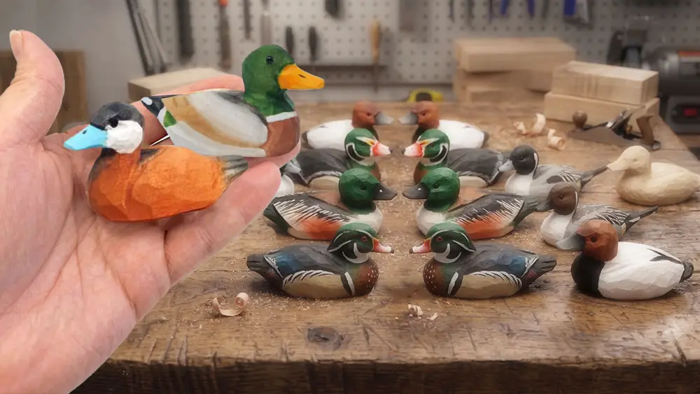 Artisan holding detailed hand-painted wooden mallards and teal ducks near the workbench