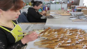 Artisans hand-painting custom wooden pens on the manufacturing lines, showcasing the reliable B2B wholesale production capacity of handcrafted novelty animal stationery.