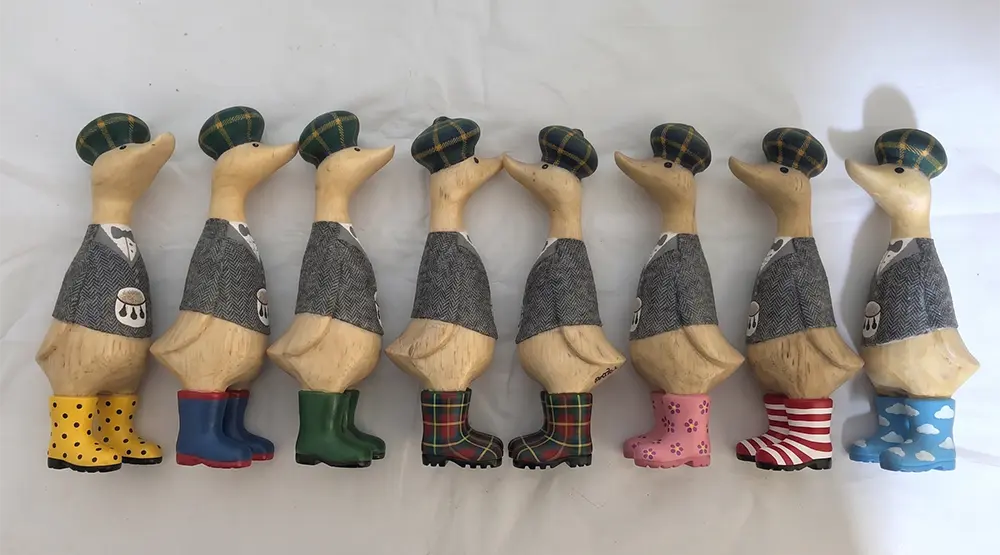 Hand-painted wooden Welly Ducklings wearing colorful customized rain boots for spring gift collection.