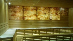Premium backlit Himalayan salt block wall installed in a high-end commercial dry sauna behind wooden benches.