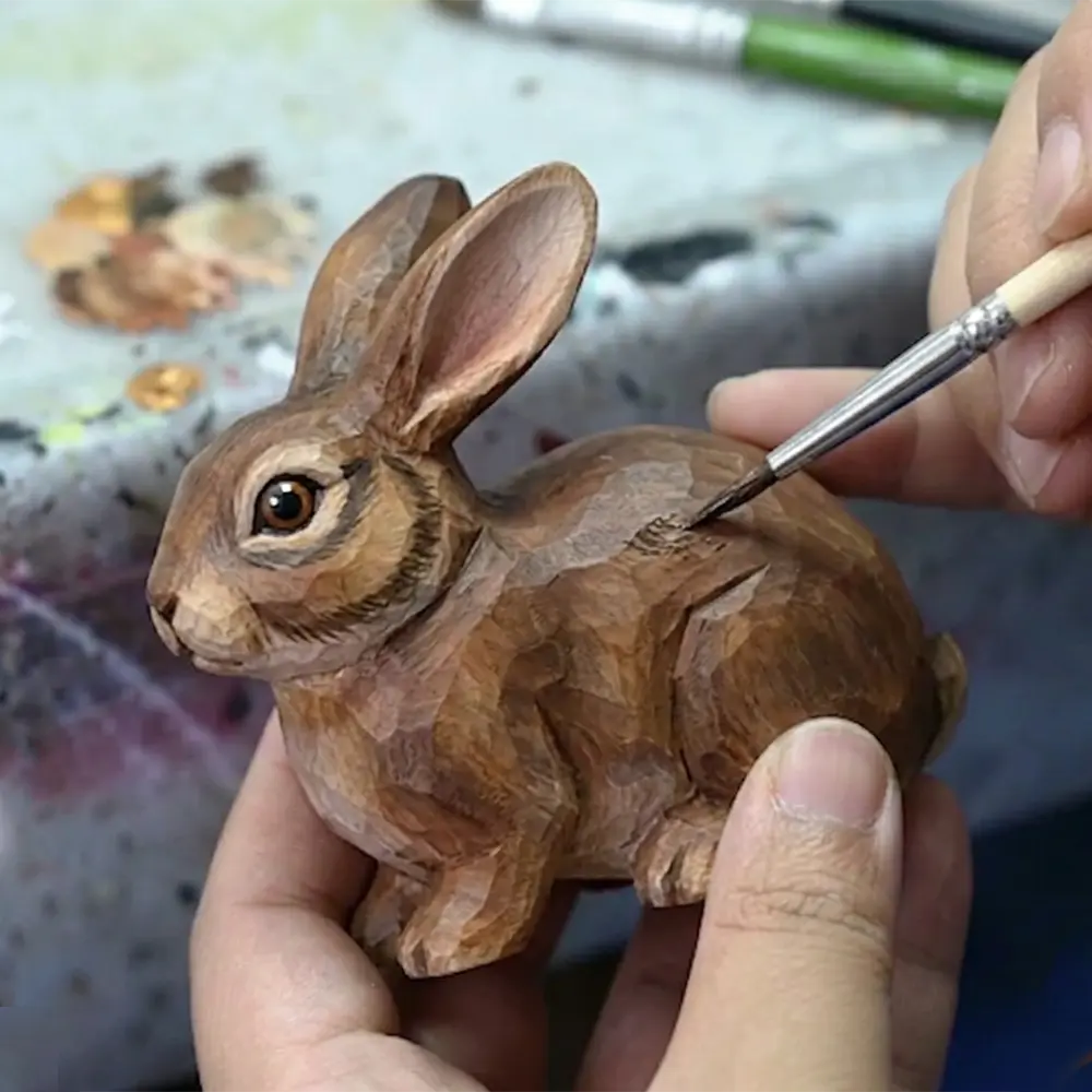 Wholesale wooden easter decor: artisan hand-painting a carved wooden rabbit