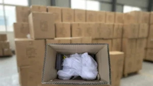 Close-up of protective packaging inside a shipping box with a warehouse inventory background.