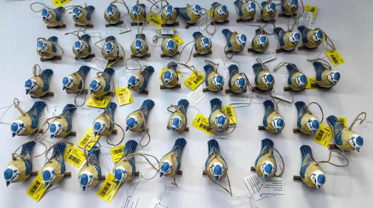 Row of hand-painted wooden bird carvings in basswood at factory, ready for B2B wholesale