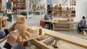 Master artisan hand-carving a wooden owl decor item in Jilin Province Ever Creation Technology Co., Ltd. workshop, demonstrating precision OEM custom craftsmanship.