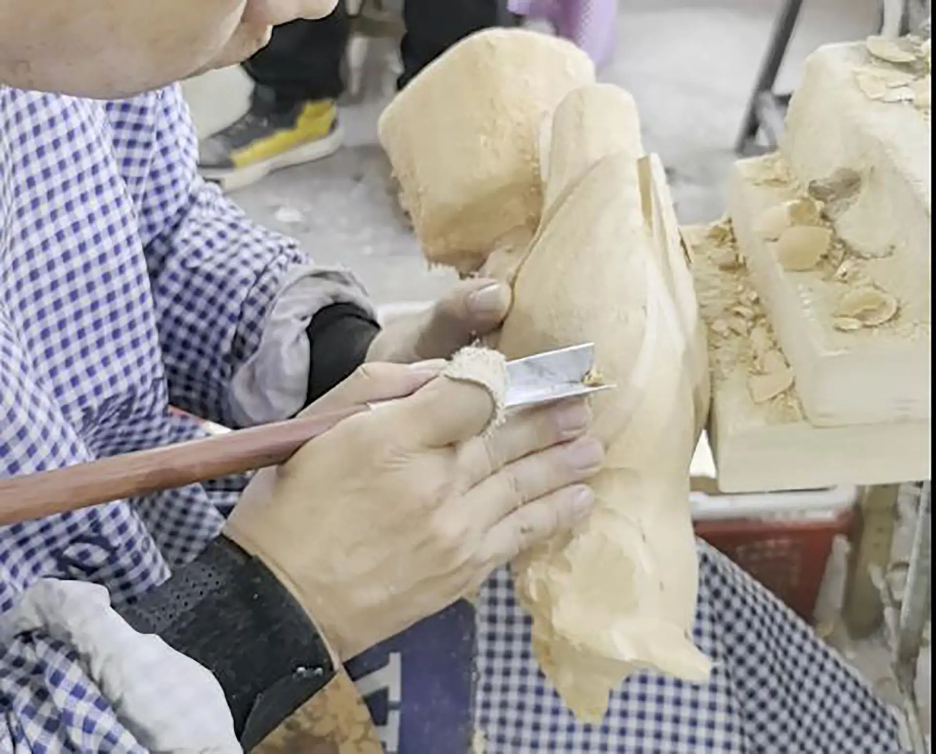 Artisan hand-carving wooden sculptures with traditional chisels at the factory. Timber Traceability