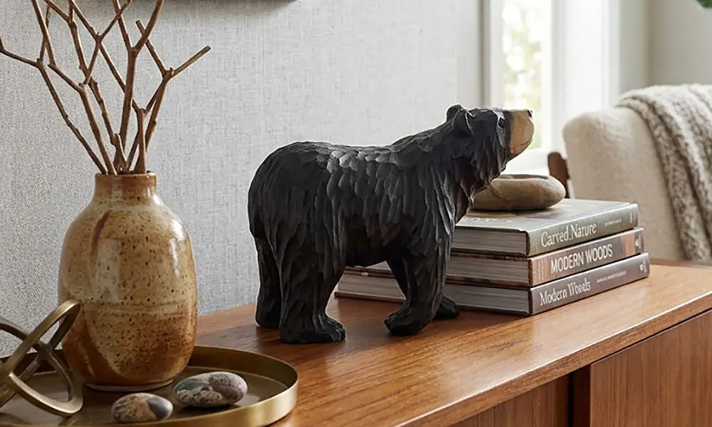 Hand-carved wooden black bear statement piece styled on a modern entryway console table with books and home decor.