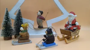 Wholesale hand-carved wooden Christmas ornaments featuring skiing animals and Santa sleigh for seasonal retail display